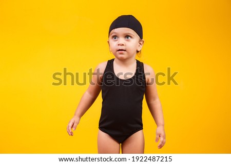 Little girl wearing beach outfit on yellow background. Summer and Vacation Concept