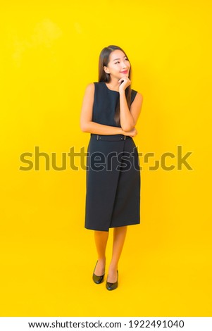 Portrait beautiful young asian business woman smile with action on yellow color background