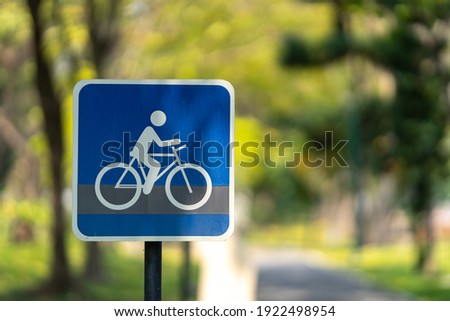 Bicycle path symbol sign with green nature blurred background.