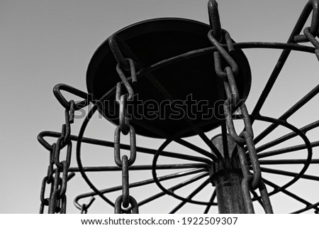Black and white picture of a disc golf disc on top of a disc golf basket.