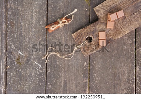 Pieces of chocolate and cinnamon sticks on a wooden board, photo rusticstyle