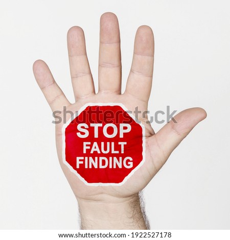 On the palm of the hand there is a stop sign with the inscription - STOP FAULT FINDING. Isolated on white background.