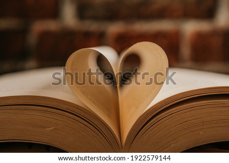 Opened book on a pile of old books.  Study education concept. Heart created from a sheet of a book. Library education