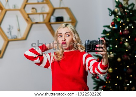 Close female portrait with beautiful smile with dimples and curls on blond hair. Woman holds camera lady photographer. Concept of happiness, new year, christmas, photographer works.