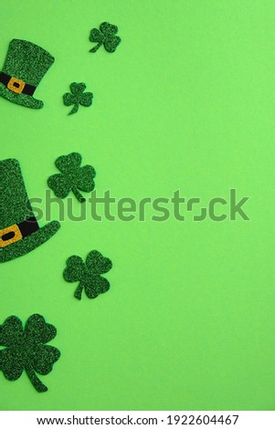 St Patricks Day frame of leprechaun hats and shamrock four leaves clover on green background. Saint Patrick's day vertical banner design. Flat lay, top view.