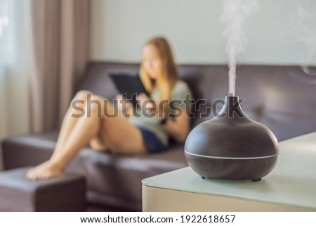 Aromatherapy Concept. Wooden Electric Ultrasonic Essential Oil Aroma Diffuser and Humidifier. Ultrasonic aroma diffuser for home. Woman resting at home Royalty-Free Stock Photo #1922618657