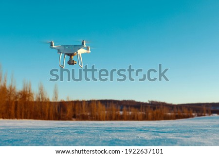 Drone flying above field covered with snow on sunny winter day Royalty-Free Stock Photo #1922637101