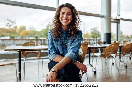 Portrait of a successful businesswoman sitting in office. Beautiful female professional looking at camera and smiling.