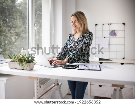 Businesswoman working at ergonomic standing workstation. Royalty-Free Stock Photo #1922656352