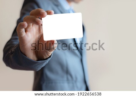 close up attractive business man holding blank white mock up card in hand. Royalty-Free Stock Photo #1922656538
