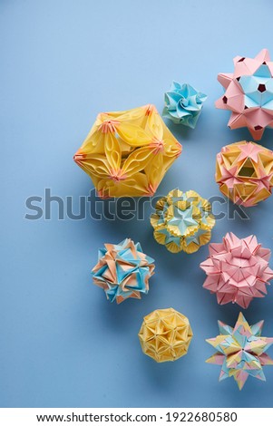Set of multicolor handmade modular origami balls or Kusudama Isolated on blue background. Visual art, geometry, art of paper folding, paper crafts. Top view, close up, selective focus, copy space.
