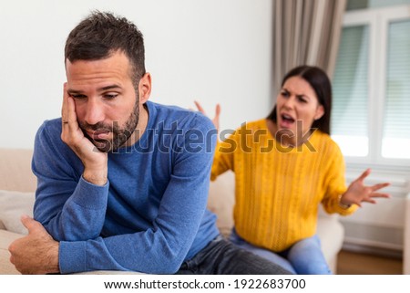 Young couple having argument - conflict, bad relationships. Angry fury woman. Angry young couple sit on couch in living room having family fight or quarrel suffer from misunderstanding Royalty-Free Stock Photo #1922683700