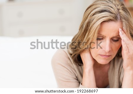 Woman suffering from stress or a headache grimacing in pain as she holds the back of her neck with her other hand to her temple, with copyspace Royalty-Free Stock Photo #192268697