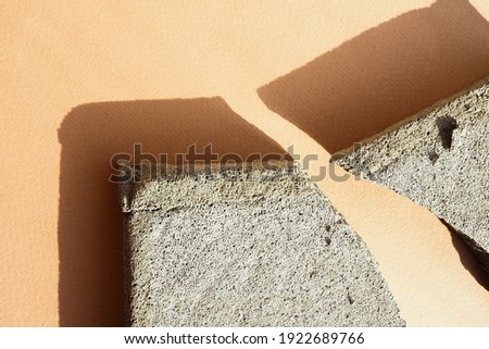several concrete chips on a beige paper background in harsh light with shadows. flat layout, top view.
