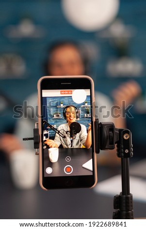 Close up of influencer vlogger record live broadcast looking at smartphone on tripod at home studio podcast. Creative content creator making online video for subscribers audience Royalty-Free Stock Photo #1922689841