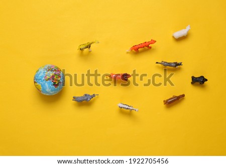 Toy wild animals and a model of the planet earth on yellow background. Save the planet concept