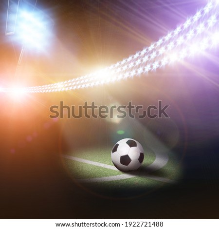 Black and white ball on a football field with green grass and stadium light stand