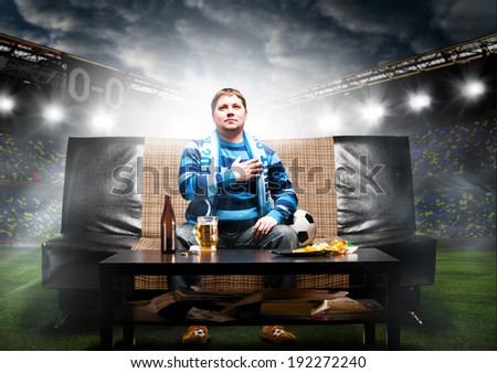 happy soccer or football fan with hand on heart on sofa at stadium Royalty-Free Stock Photo #192272240