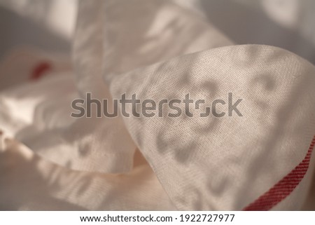 Abstract background. Lightweight cotton fabric with pleats. Shadows from curtains on fabric.