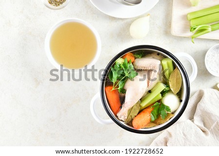 Chicken broth with vegetables and spices on light stone background with free text space. Healthy diet dish for dinner. Top view, flat lay 
