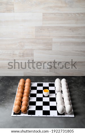 Chessboard with figures of white and brown eggs on a gray background. Creative Idea Easter and chess. Place for text