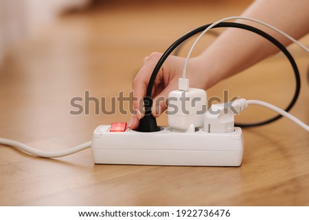 Woman pluging the wire into white extension cord. Close up of female hand put cabel Royalty-Free Stock Photo #1922736476