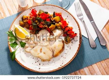 Fried steak of blue shark with vegetable garnish of baked zucchini, red peppers and fresh lemon