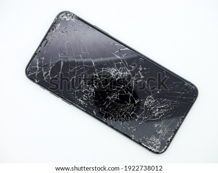 Modern space grey smartphone with a broken glass display and damaged curved body close-up isolated on white background