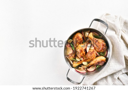 Chicken drumsticks baked with apples and herbs. White background with free text space, top view, flat lay