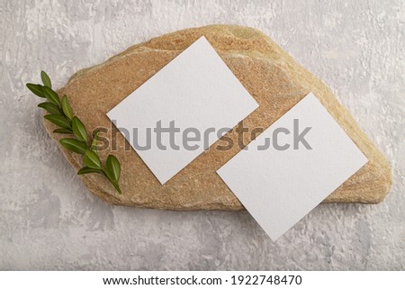 White paper business card, mockup with natural stone and boxwood branch on gray concrete background. Blank, flat lay, top view, still life, canvas, copy space.