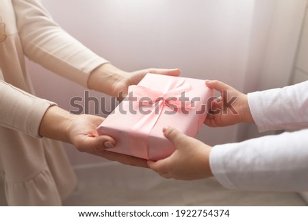 Kid giving gift box to mum. Holidays, present, childhood concept. Close up of child and mother hands with gift box on white background. Mothers day, Womens day (March 8), Easter