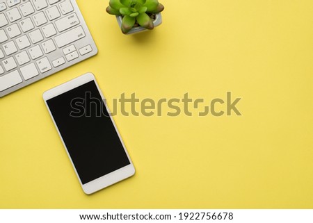 Photo above of plant keyboard and phone isolated on the yellow background