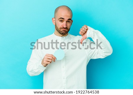 Young caucasian bald man celebrating world water day isolated on blue background showing a dislike gesture, thumbs down. Disagreement concept.