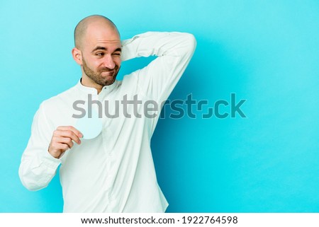 Young caucasian bald man celebrating world water day isolated on blue background touching back of head, thinking and making a choice.