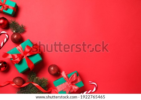 Gift boxes and Christmas decorations on red background, flat lay. Space for text