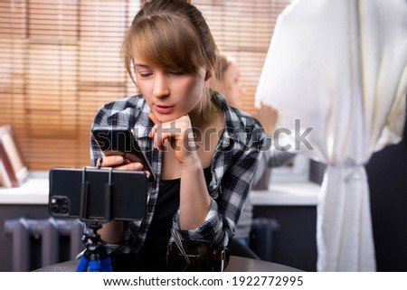 Female blogger influencer hold phone sit at office table. Girl vlogger shoot social media post on smartphone get many likes emoji. Closeup view. High quality photo