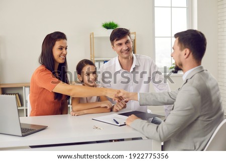 Happy family with child meeting with manager at real estate agency. Smiling husband and wife shaking hands with agent and thanking him for help. Buying new house and signing purchase agreement concept