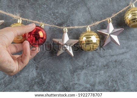 A man hanging colorful ornaments from the rustic thread on grey background