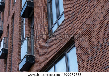 Facade of a red brick house with panoramic windows and french balcony. Detailed pictures of exterior urban architecture. Minimal modern geometric architecture shape. Modern architecture of Moscow