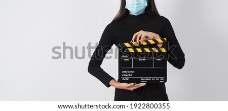 Asian woman wear face mask or medical mask and hand's hold black clapper board or movie slate use in video production ,film, cinema industry on white background.