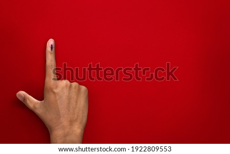 male Indian Voter Hand with voting sign or ink on red background with copy space election commission of India
