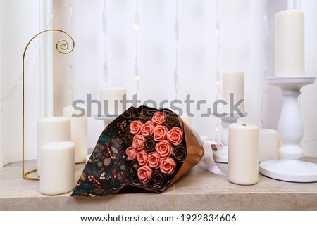 bouquet of roses made of chocolate lies on the marble base of the fireplace among the candles.