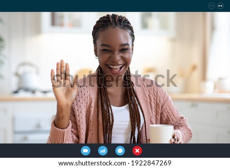 Cheerful Black Woman Having Video Conference, Making Web Call While Drinking Coffee In Kitchen, African Lady Waving Hand At Camera, Greeting Somebody, Enjoying Online Communication, Screenshot View Royalty-Free Stock Photo #1922847269