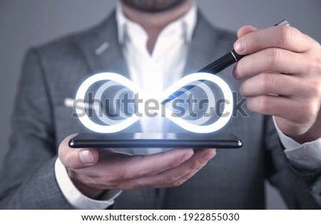 Man holding smartphone with a Infinity symbol.