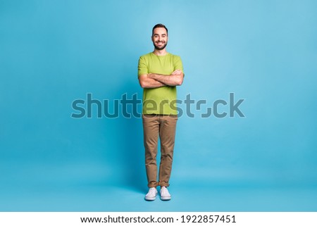 Full size photo of charming young confident man hold hands folded wear green t-shirt isolated on blue color background