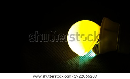 The LED light is yellow on a black cloth background
