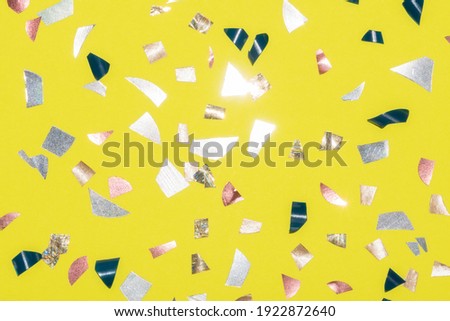 shiny metallic confetti on a bright yellow background terrazzo style