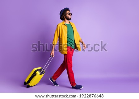 Full size profile portrait of positive dark skin guy carry suitcase look empty space isolated on purple color background Royalty-Free Stock Photo #1922876648