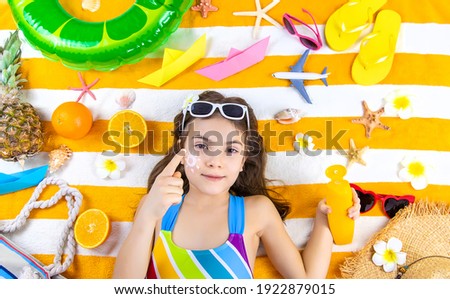 A child girl smears sunscreen on her skin. Selective focus. Kid.