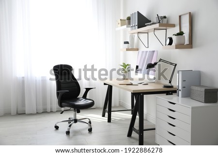 Comfortable office chair near table with modern computer Royalty-Free Stock Photo #1922886278